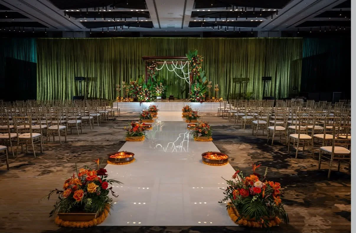 Wide view of seating and floral aisle leading to a green stage